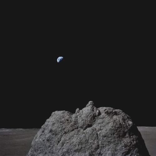 A rocky lunar surface with Earth visible in the dark sky, showcasing the vastness of space.