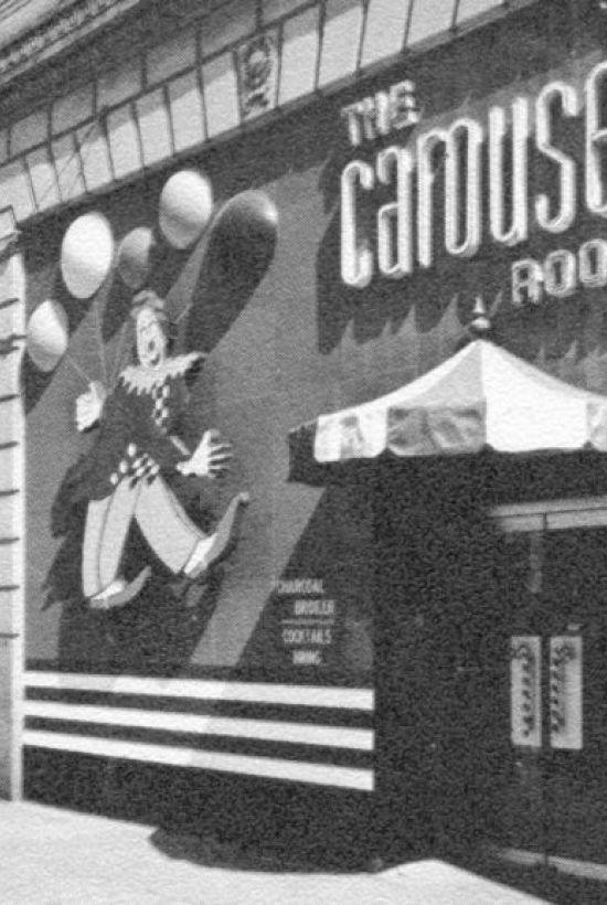 A black-and-white image of "The Carousel Room" entrance, featuring a jester illustration and marquee lighting.
